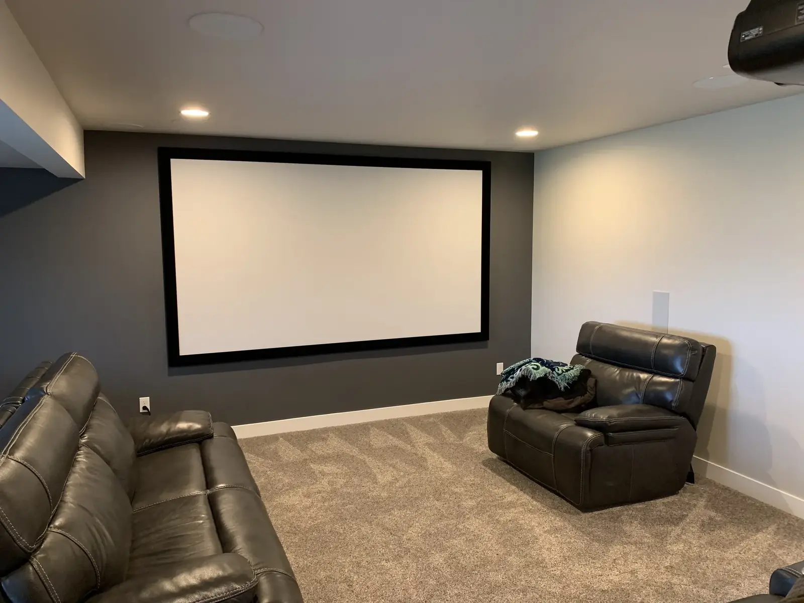 Basement home theater with a projection screen and leather recliners