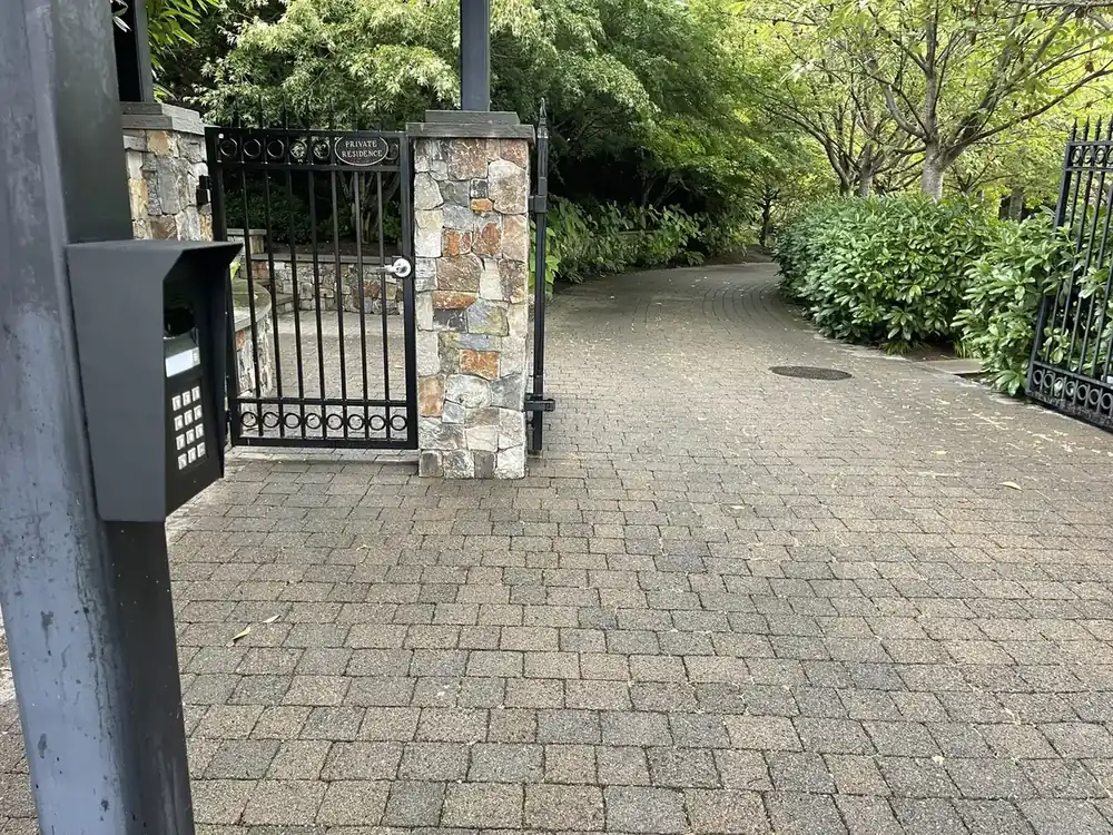 Iron driveway gate between stone pillars, with a call box on a post, Issaquah