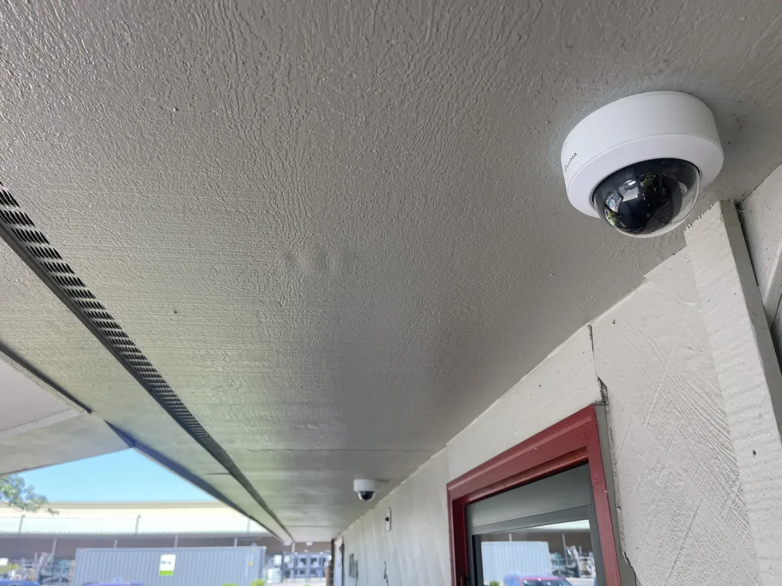 Dome security camera under a covered walkway eave, with a second camera farther along, Kent