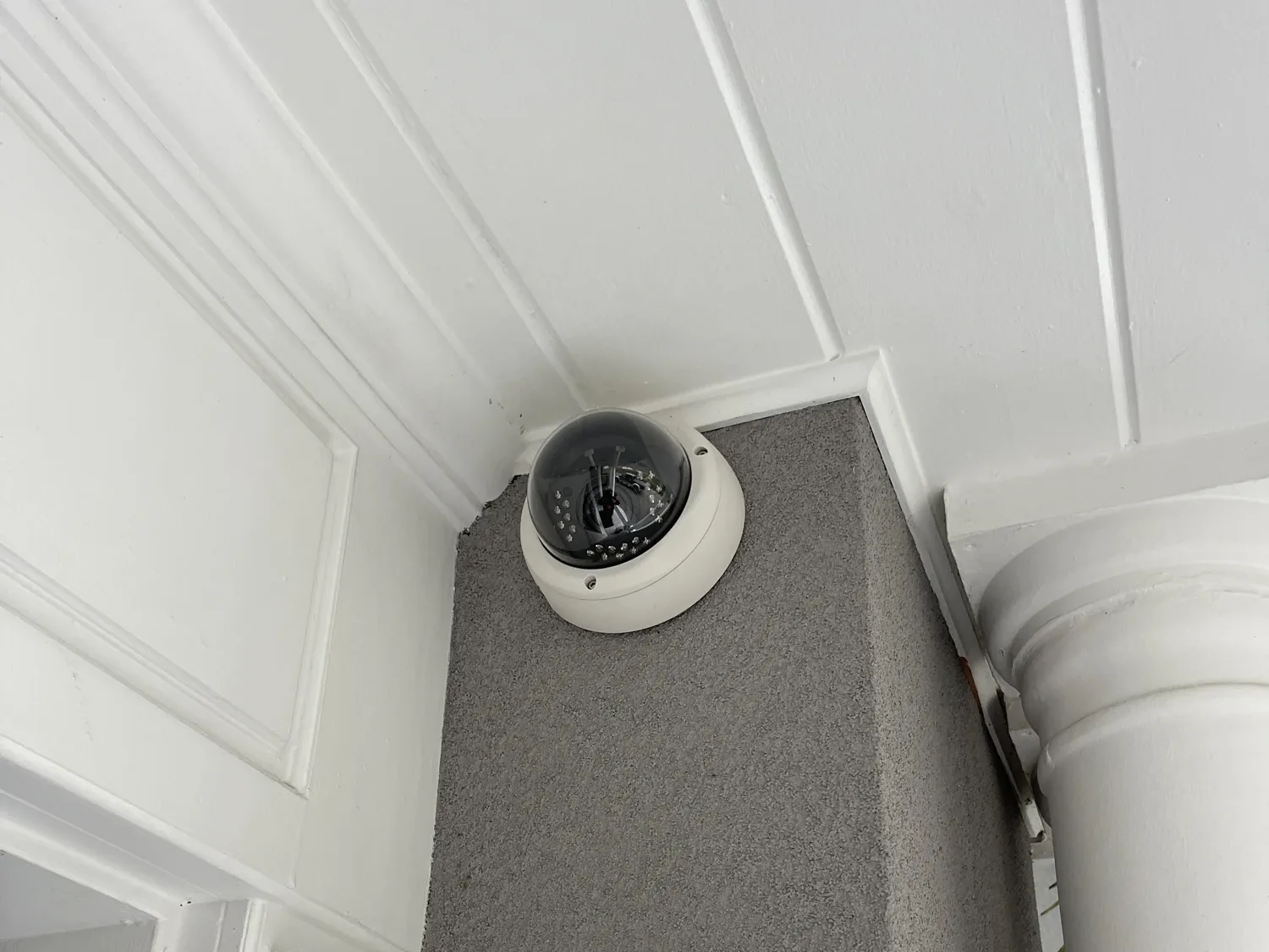 White dome security camera mounted at the top of a front porch column, Kirkland