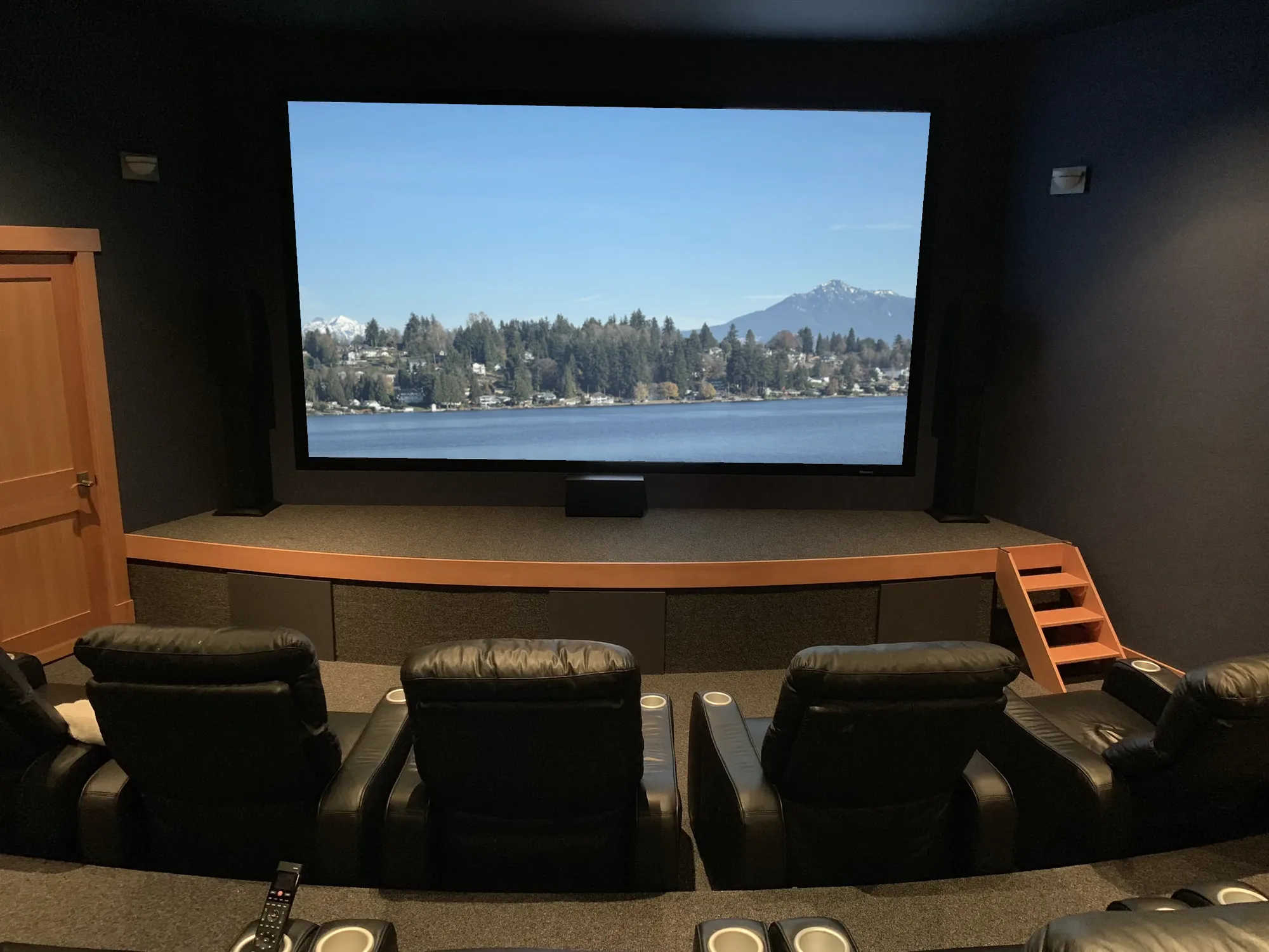 Dedicated home theater with a raised stage, a large screen and tiered recliners, North Bend