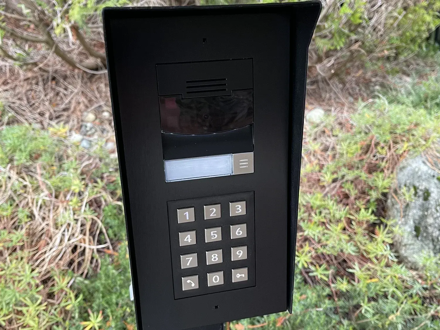 Gate call box with a camera, call button and keypad on a post at a driveway entry, Redmond
