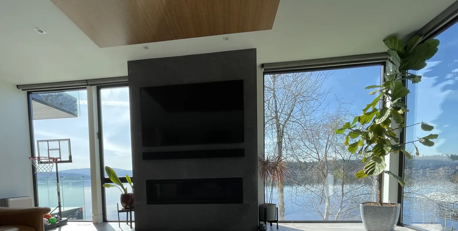 TV and soundbar mounted above a modern fireplace in a Sammamish living room with a lake view