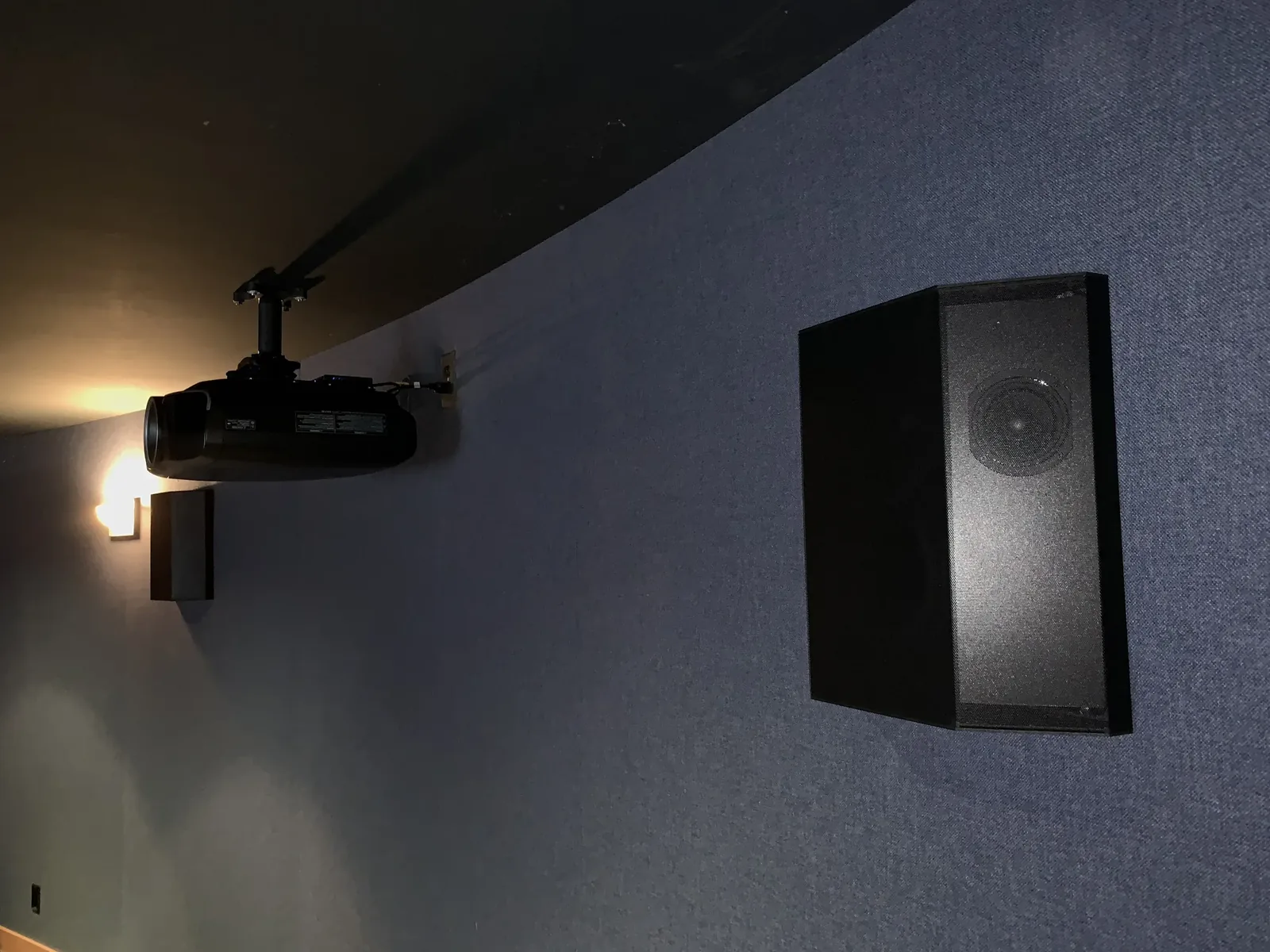 Projector and surround speaker on a fabric-covered theater wall, North Bend